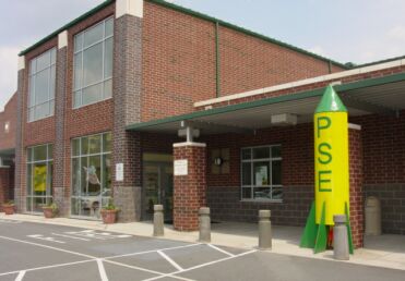 Two story brick school building with yellow rocket in front of it.